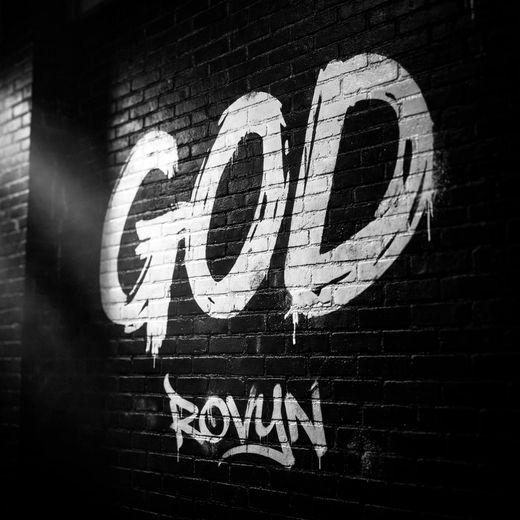 Arte gráfico "GOD" de Rovyn en blanco sobre muro de ladrillo negro